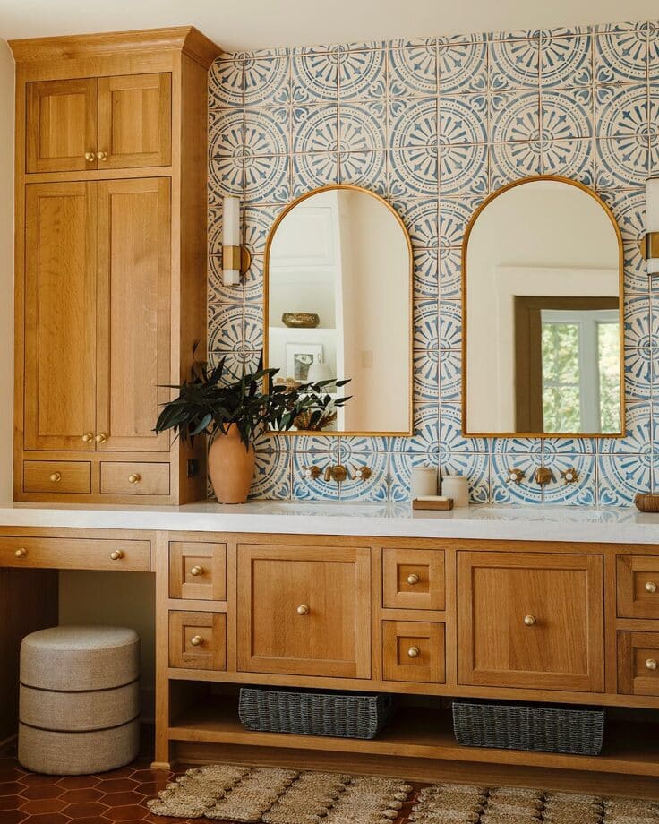 custom wood vanity with blue tile and gold mirrors