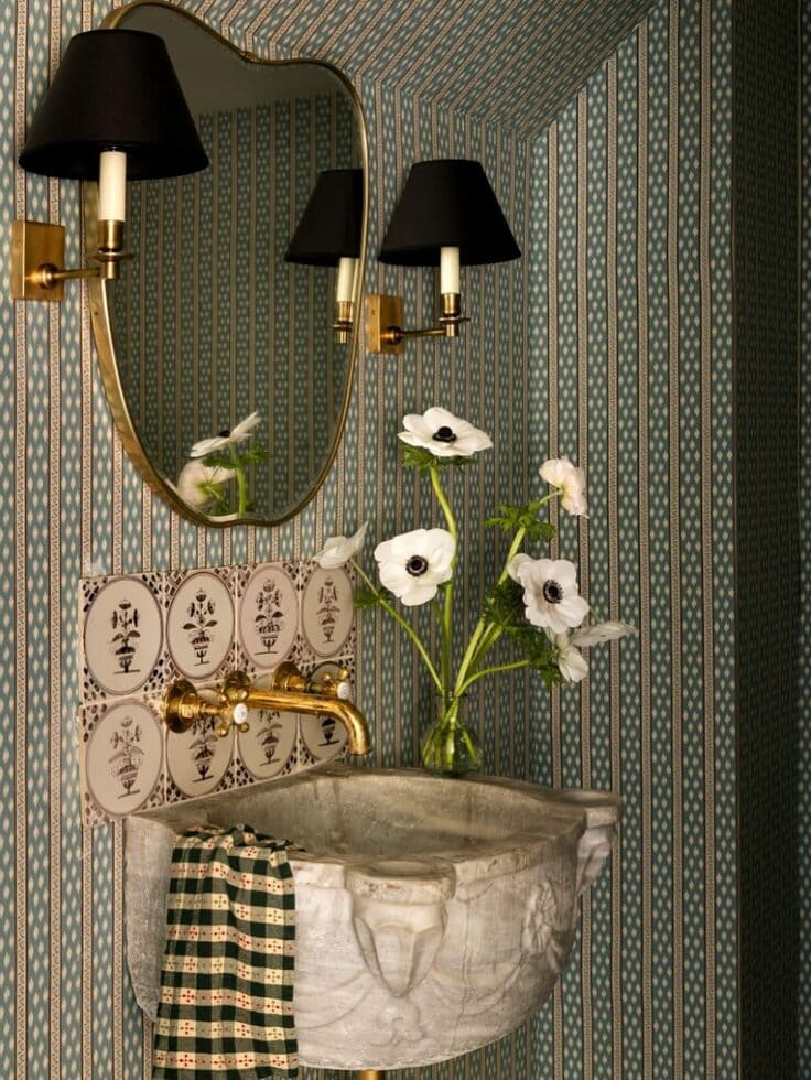 Green striped bathroom wallpaper with a carved stone basin and gold fixtures