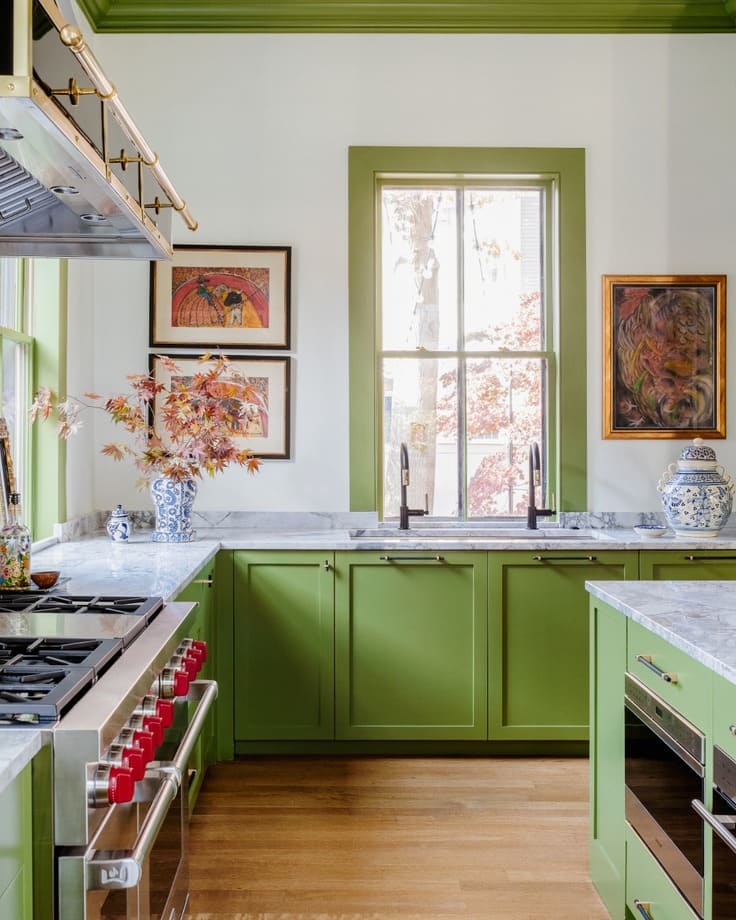 Bright kitchen featuring spring green cabinets and trim, white walls, marble countertops, and colorful framed artwork
