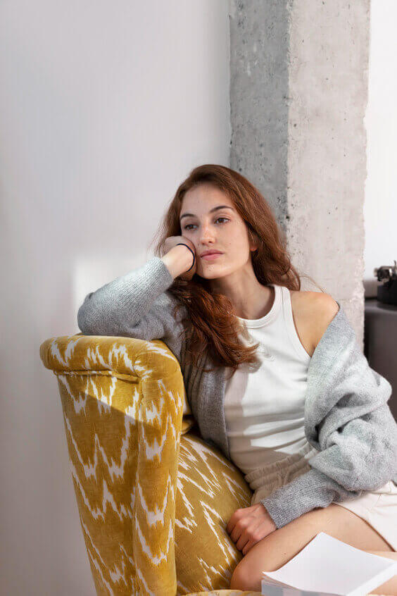 What to do when you're bored, things to do when bored, woman leaning on sofa with bored look on her face in her living room. 