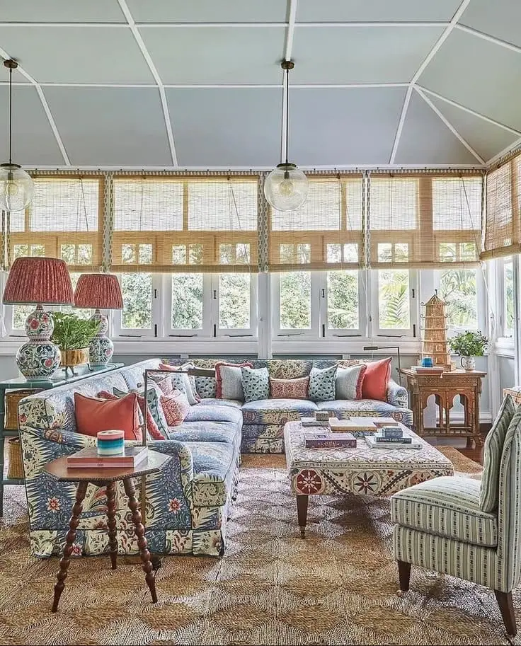 Vibrant sunroom with patterned sectional, jute rug, and decorative lamps