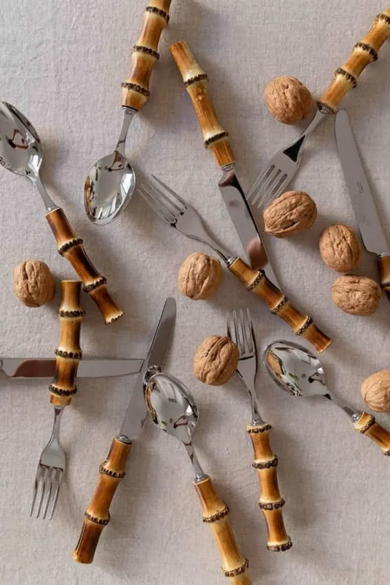 A 12-piece bamboo cutlery set arranged artistically among walnuts.