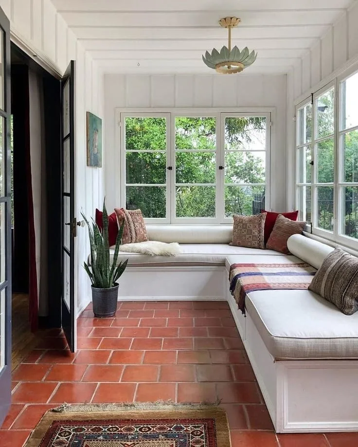 White built-in bench sunroom with terracotta tile and global-inspired pillows