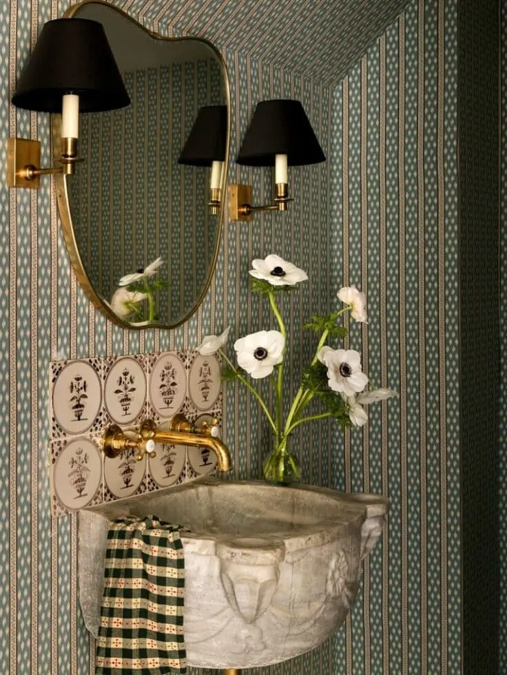 Green striped bathroom wallpaper with a carved stone basin and gold fixtures