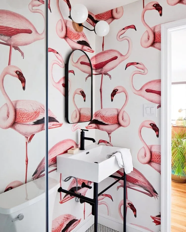 Pink flamingo bathroom wallpaper with a white sink and black fixtures