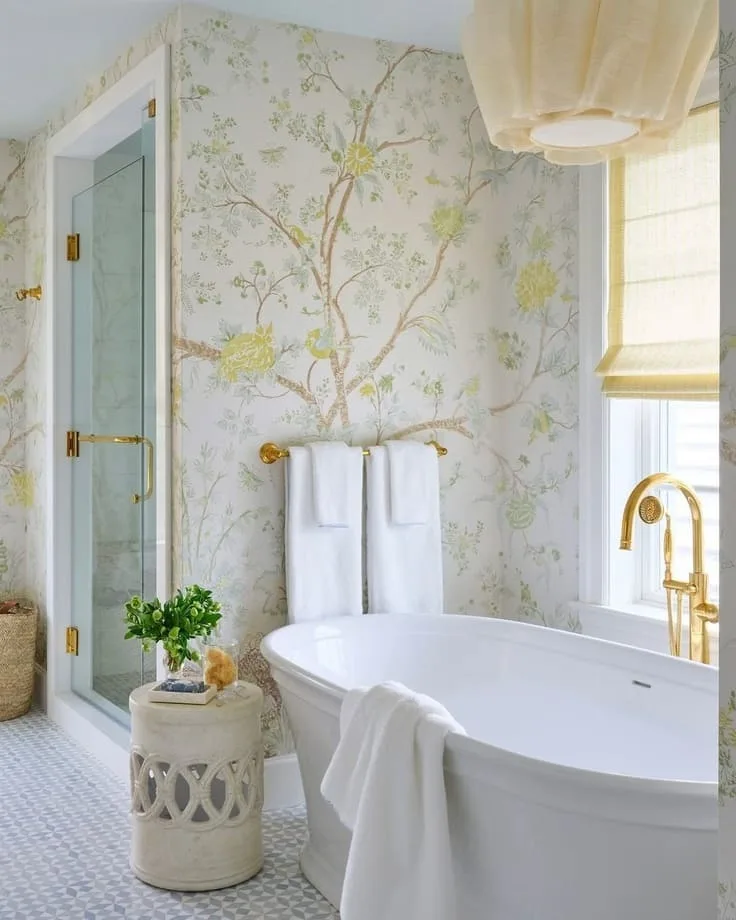 Light botanical bathroom wallpaper with a freestanding tub and gold fixtures