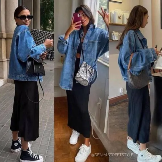 Three women wearing oversized denim jackets paired with black midi skirts, sneakers, and crossbody bags.