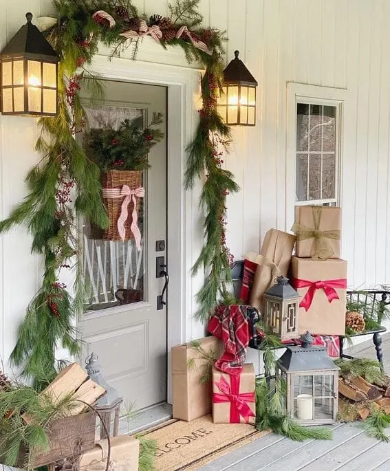 Festive porch decorated with garlands, presents, and lanterns for a cozy holiday feel.