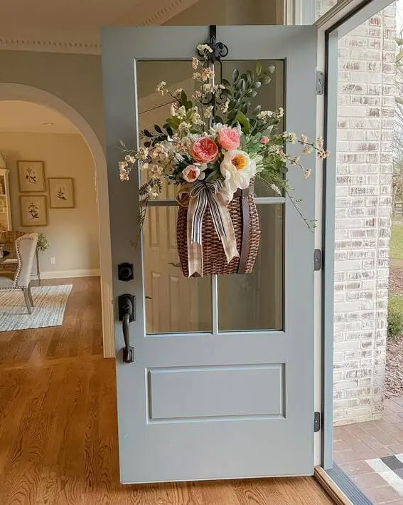 Soft blue door decorated with a basket of fresh flowers and a striped ribbon.