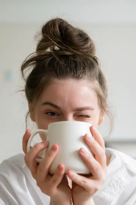 girl drinking coffee from coffee mug and winking to help boost dopamine