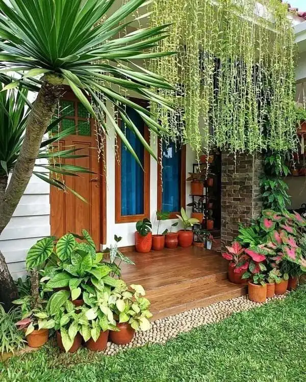 Front door decorated with vibrant potted plants and cascading greenery